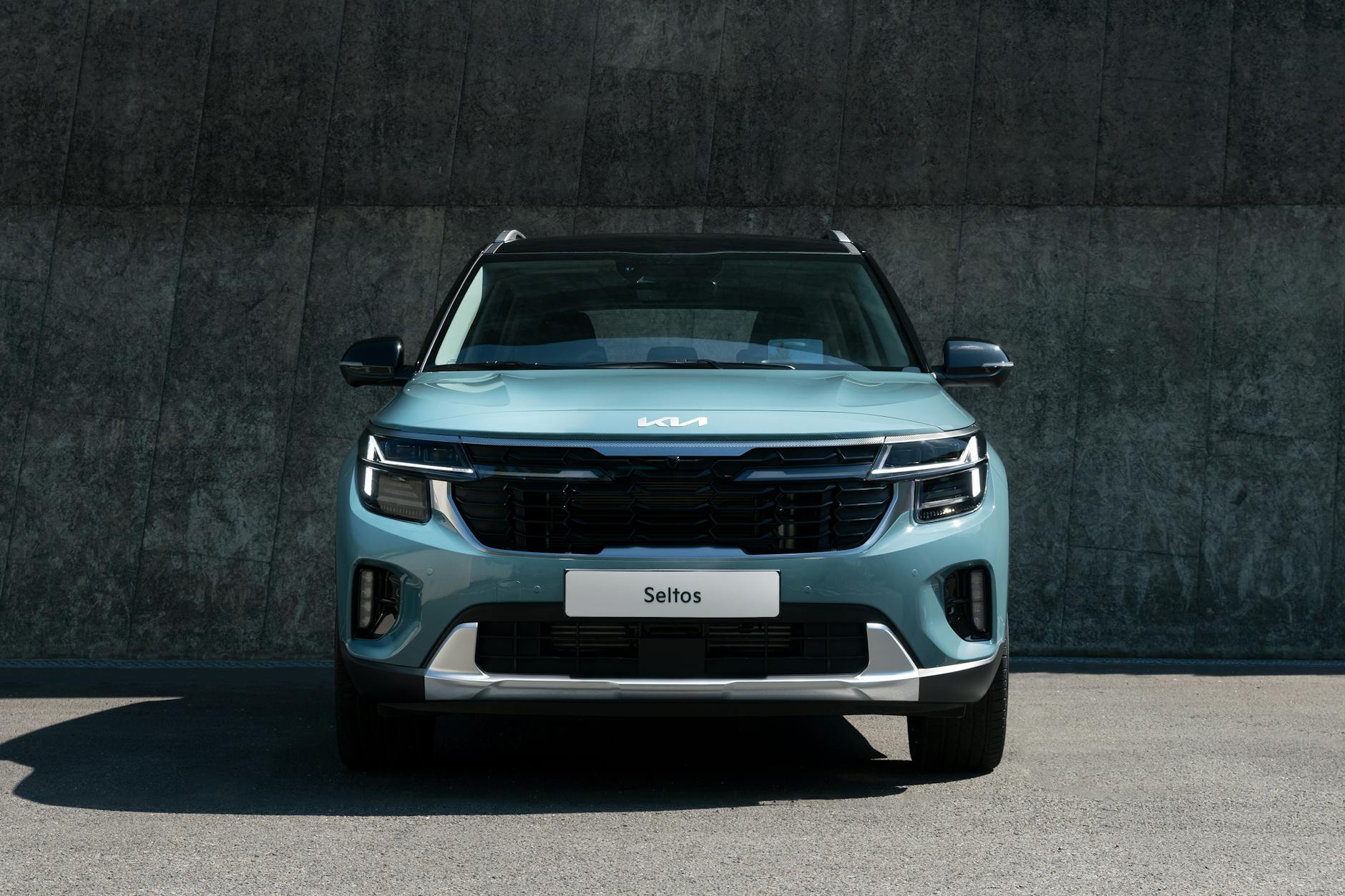 Niebieski SUV Kia Seltos zaparkowany przy betonowej ścianie