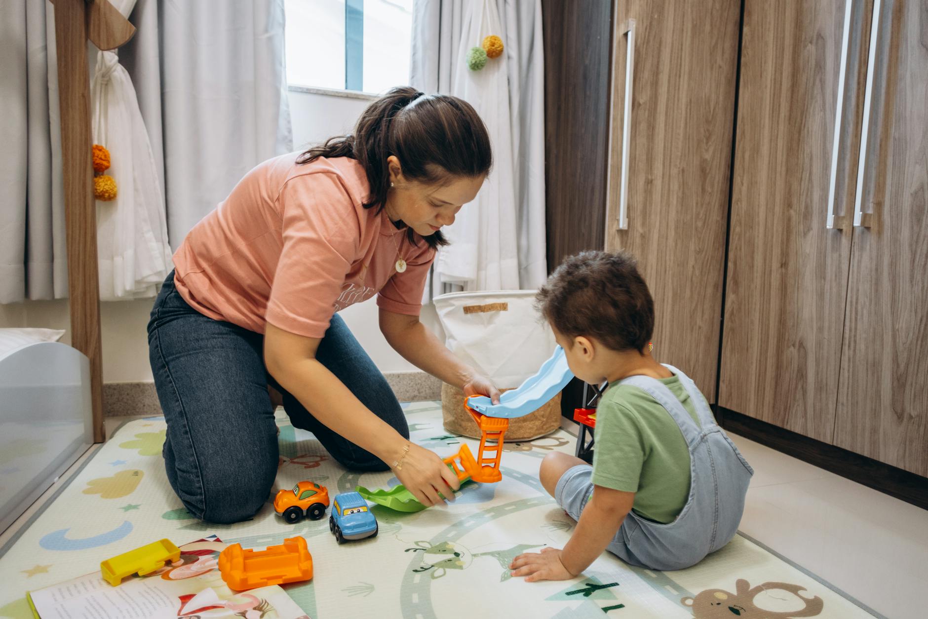 Mama z synem bawią się resorakami na podłodze w pokoju