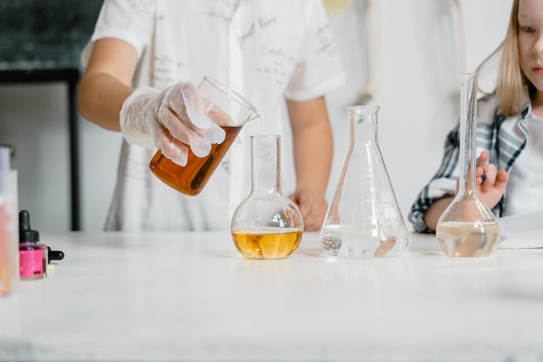 Dzieci w laboratorium mierzą pH kolorowych roztworów w zlewkach